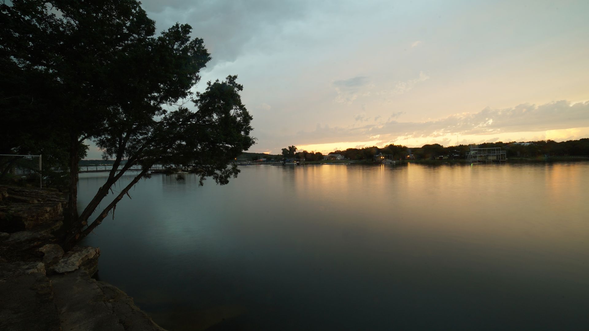 A sunset over a lake with a tree in the foreground