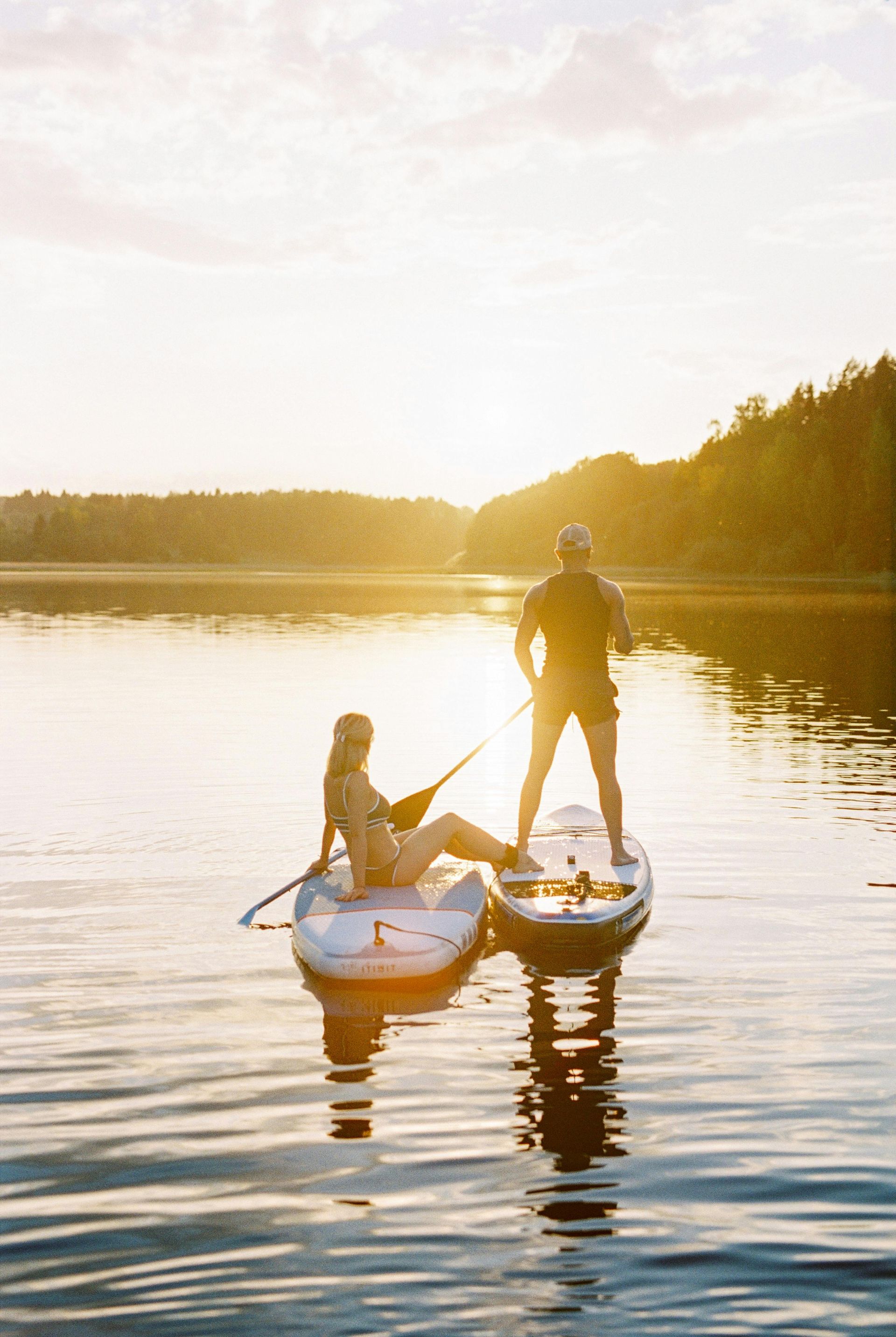 A man and a woman are standing on paddle boards in the water.