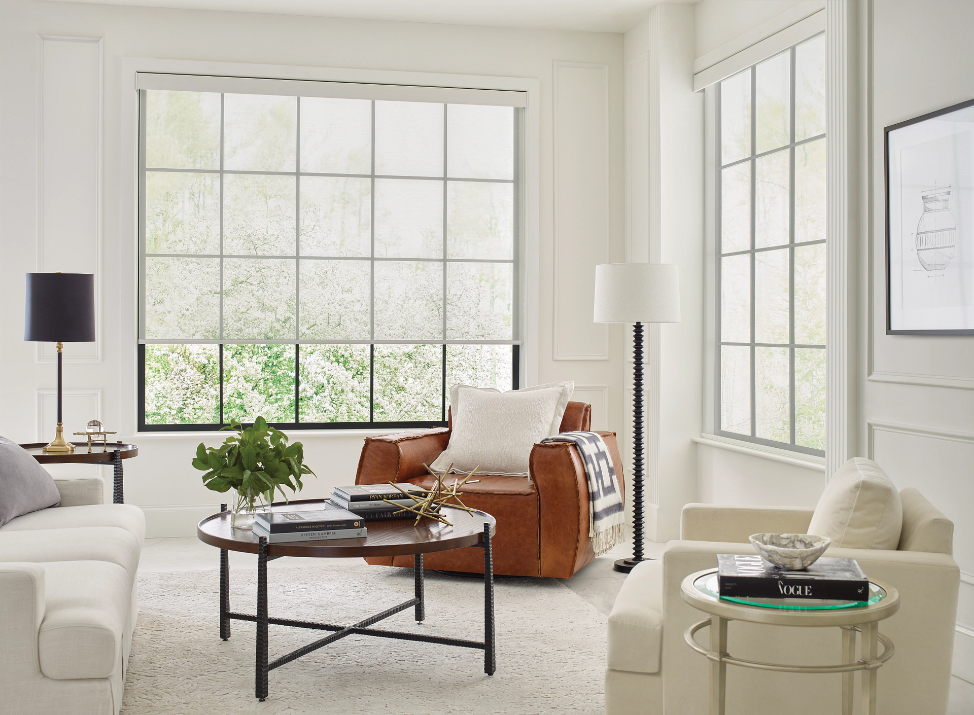 Bright living room with large windows, white furniture, a brown leather chair, and a coffee table.