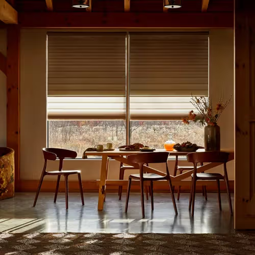 Cozy dining nook with wooden table, chairs, and warm sunlight through blinds