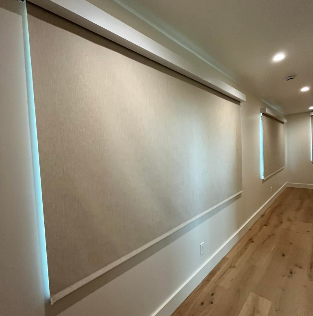 Modern hallway with beige walls, large roller shades, and light wood flooring
