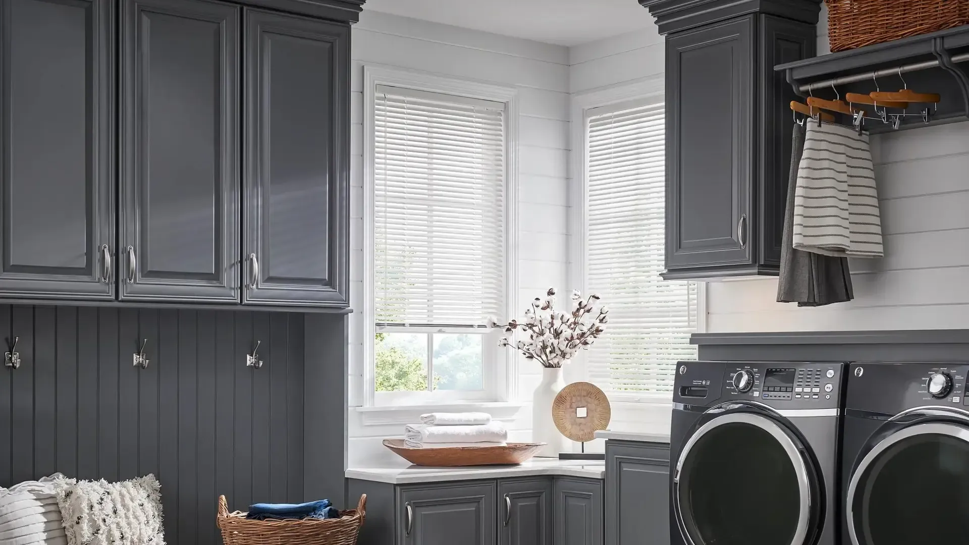 Gray laundry room with cabinets, washer and dryer, sink, and window blinds.