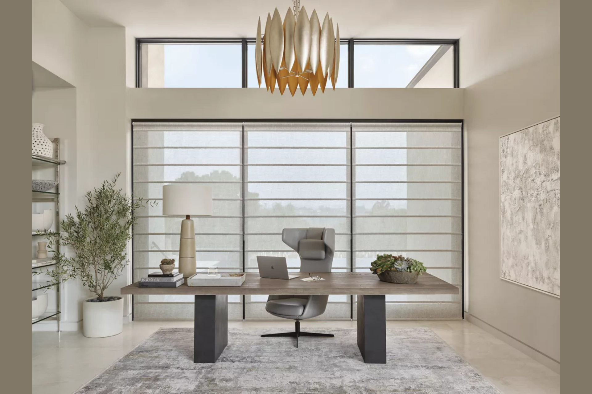 Modern minimalist office with desk, chair, wall art, large windows, and gold chandelier