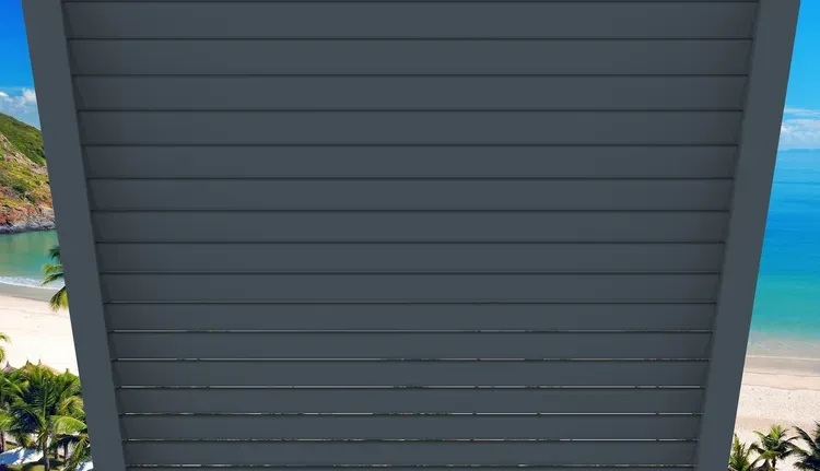 Dark gray siding wall with a narrow view of a beach and blue water on both sides