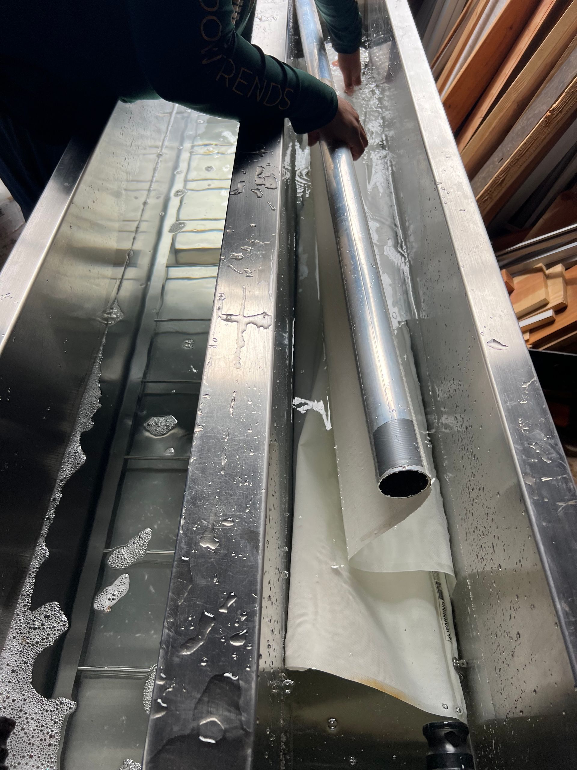 Worker positioning silver metal ducting inside an insulated ceiling cavity