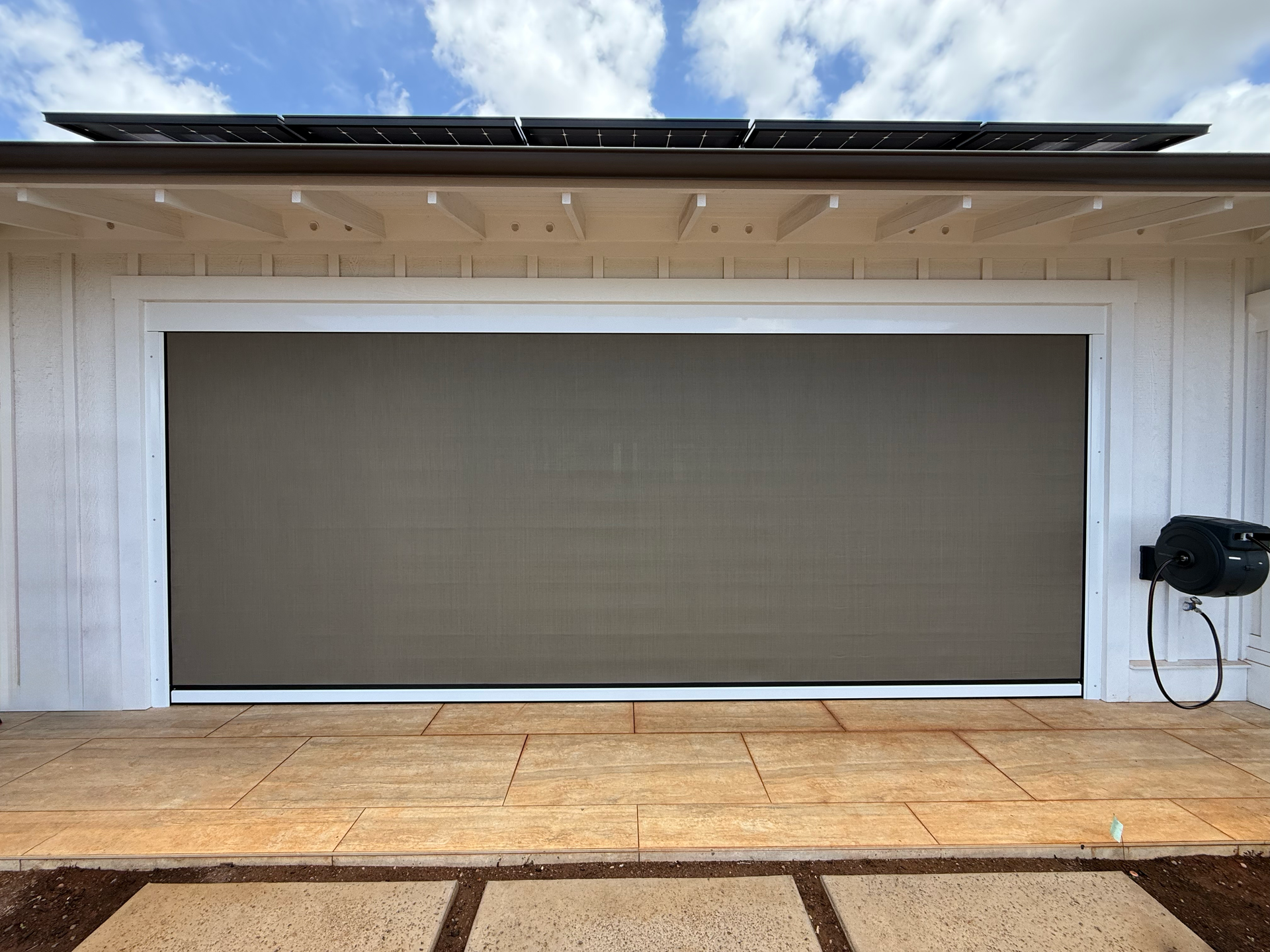 Outdoor stage with a large closed beige screen beneath a white canopy