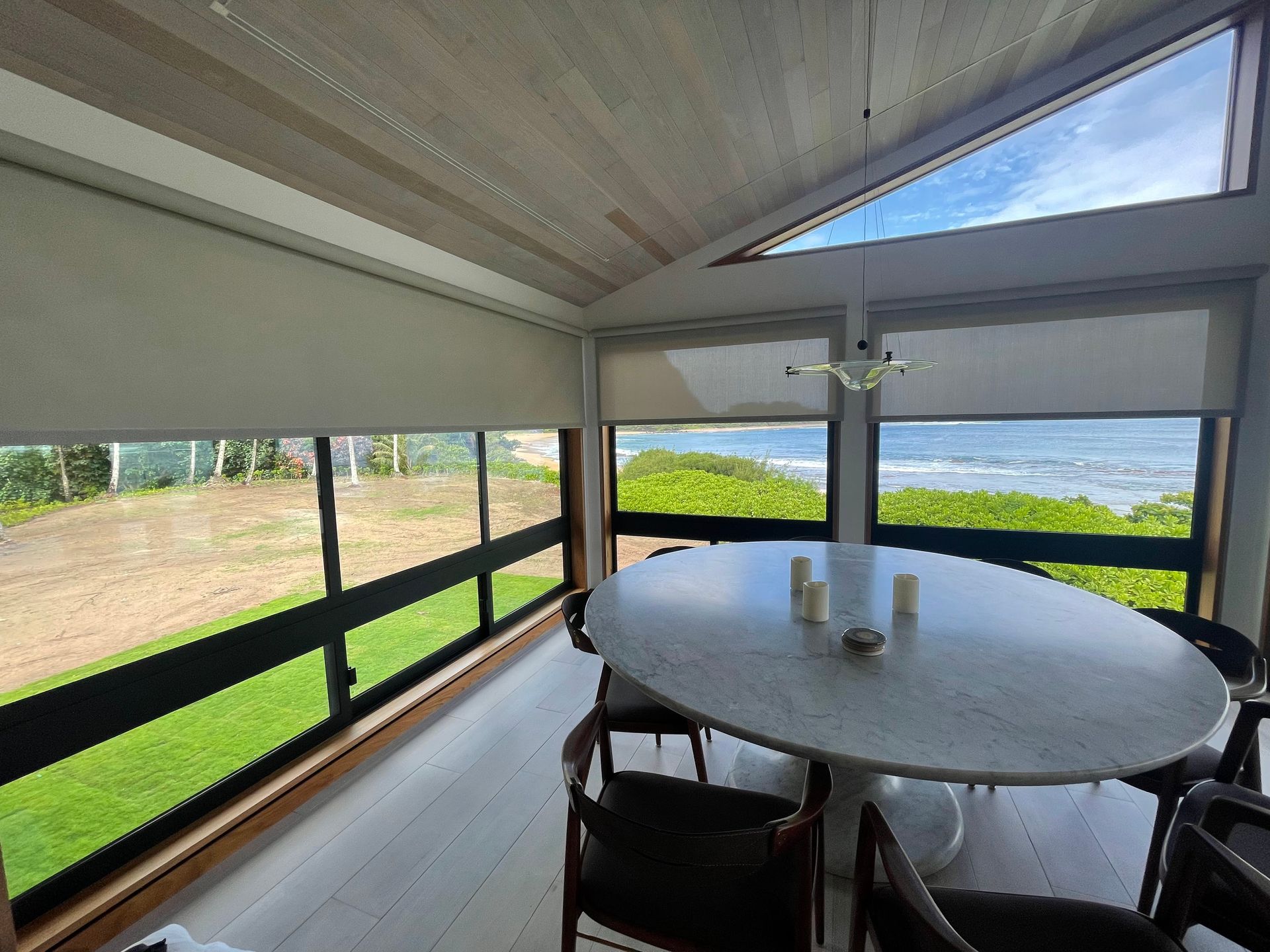 Screened porch with round table, chairs, and a lake view beyond the windows