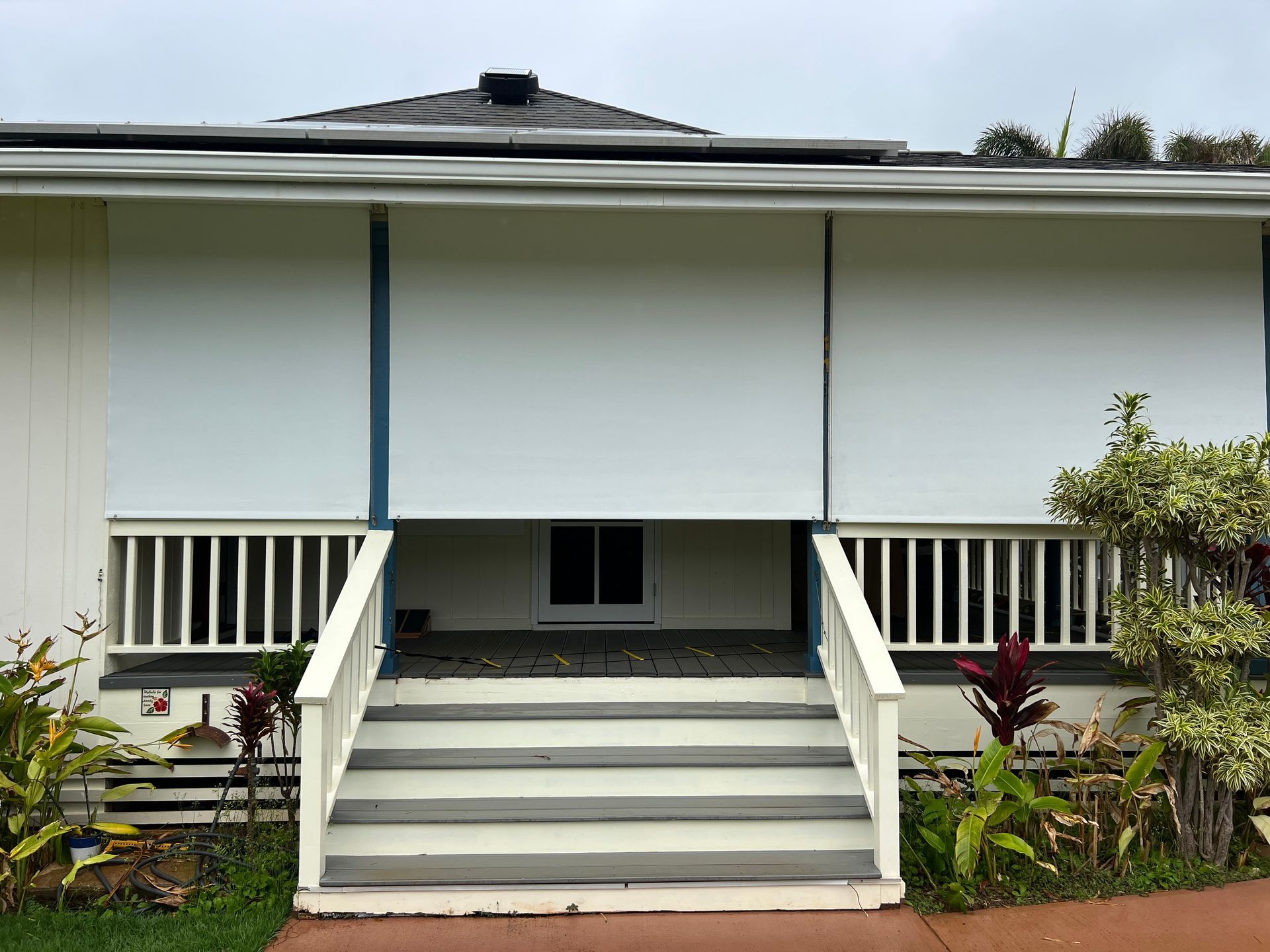 Front view of a white house with steps, central porch, and small garden beds