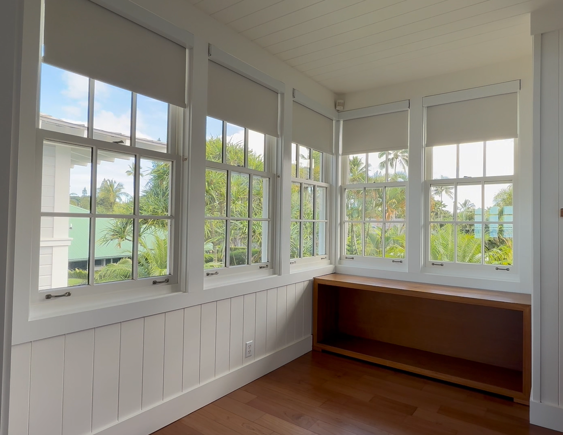 Bright sunroom with white walls, large windows, and a wooden built-in bench nook