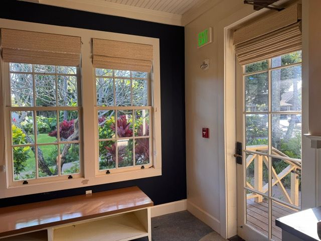 Bright room with large windows, wooden bench, and glass door opening to a garden patio