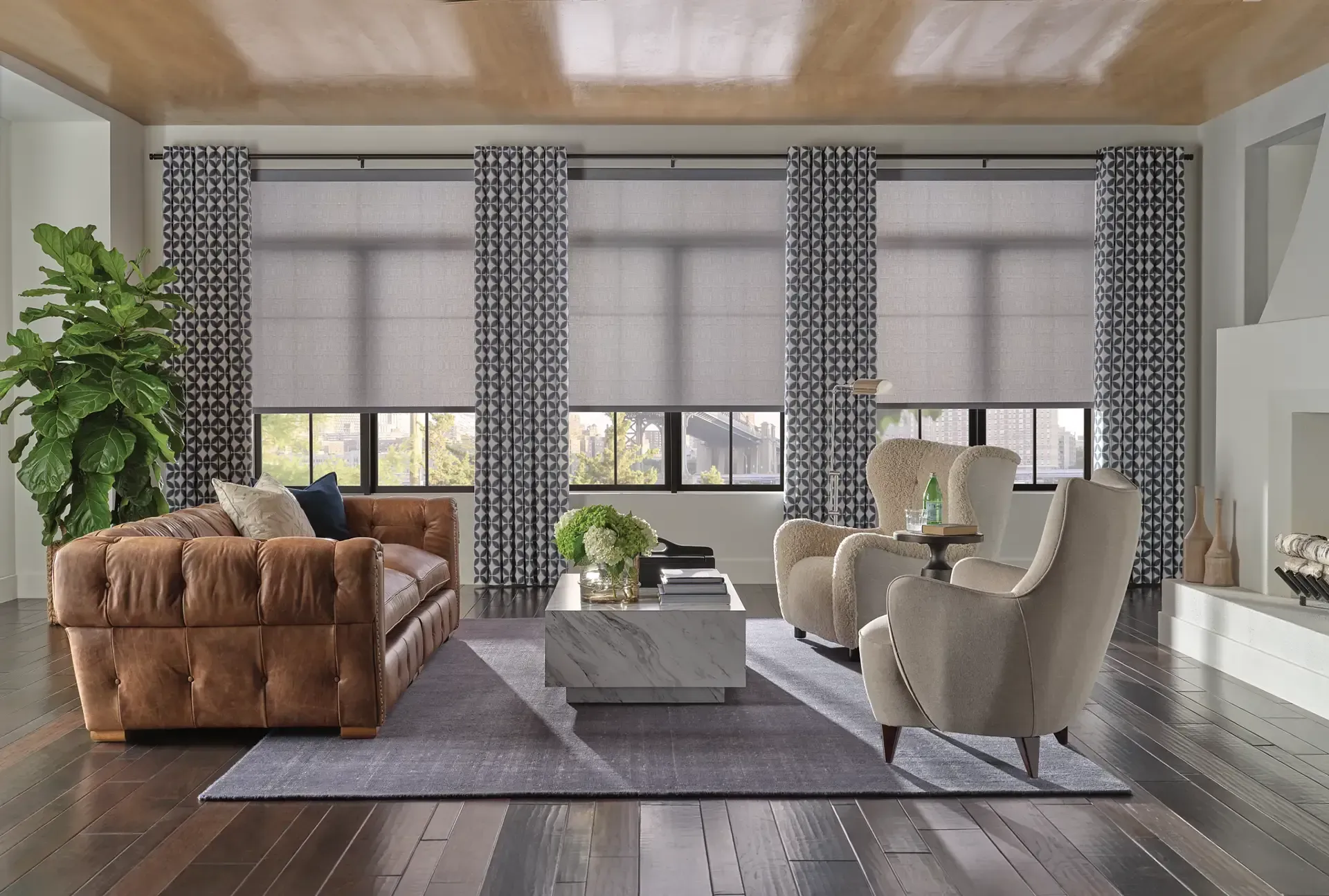 Modern living room with a brown sofa, beige chairs, large windows, and gray decor