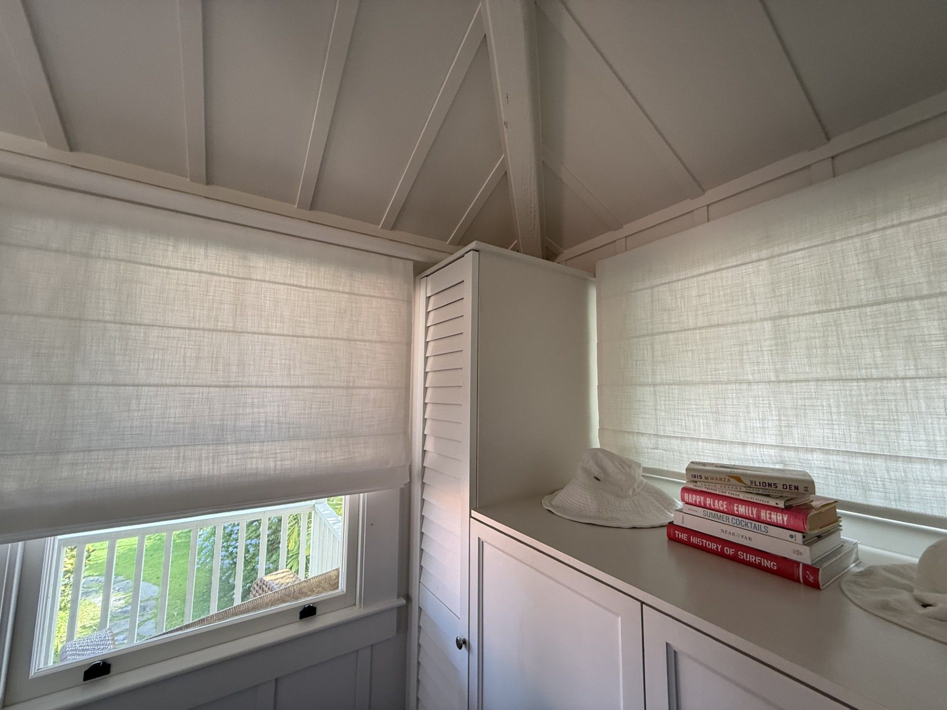 White sunroom corner with louvered cabinet, sloped ceiling, and a stack of red-labeled boxes on a counter