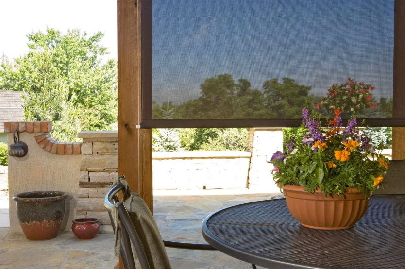 Patio with potted flowers on a round table, steps, and a shaded outdoor view.