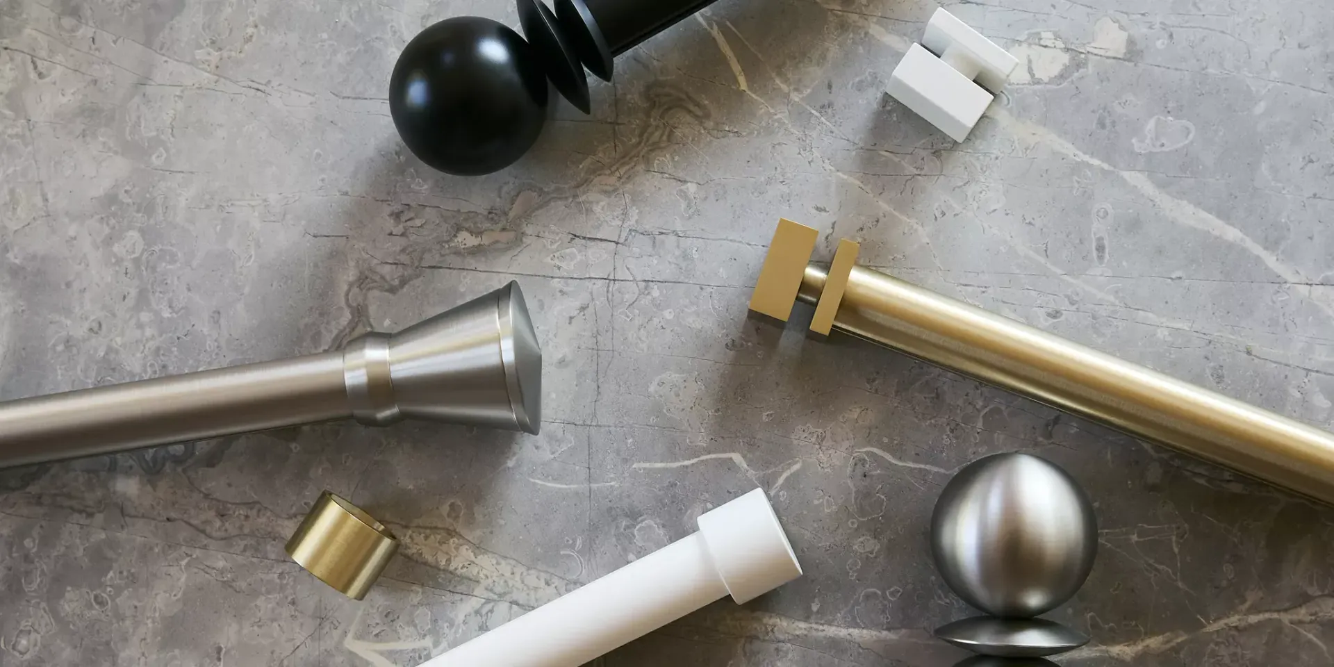 Assorted metal curtain rods and finials on a gray surface