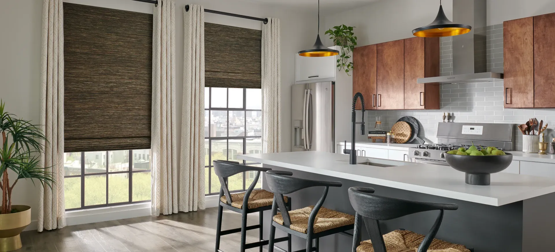 Modern kitchen and dining area with gray island, wood cabinets, black chairs, and large windows with blinds