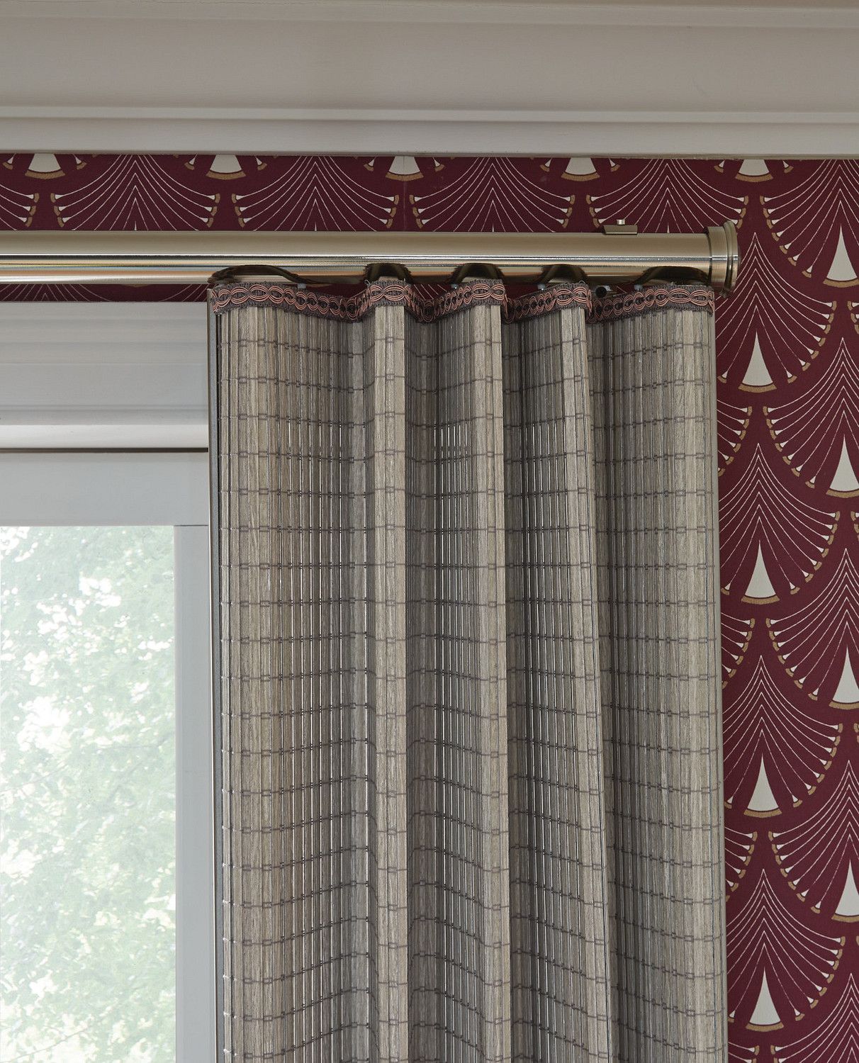 Gray curtains over a window beside red patterned wallpaper with a decorative border