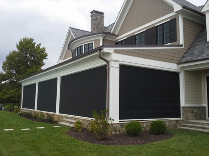 House exterior with large black-covered windows and stone siding along a manicured lawn