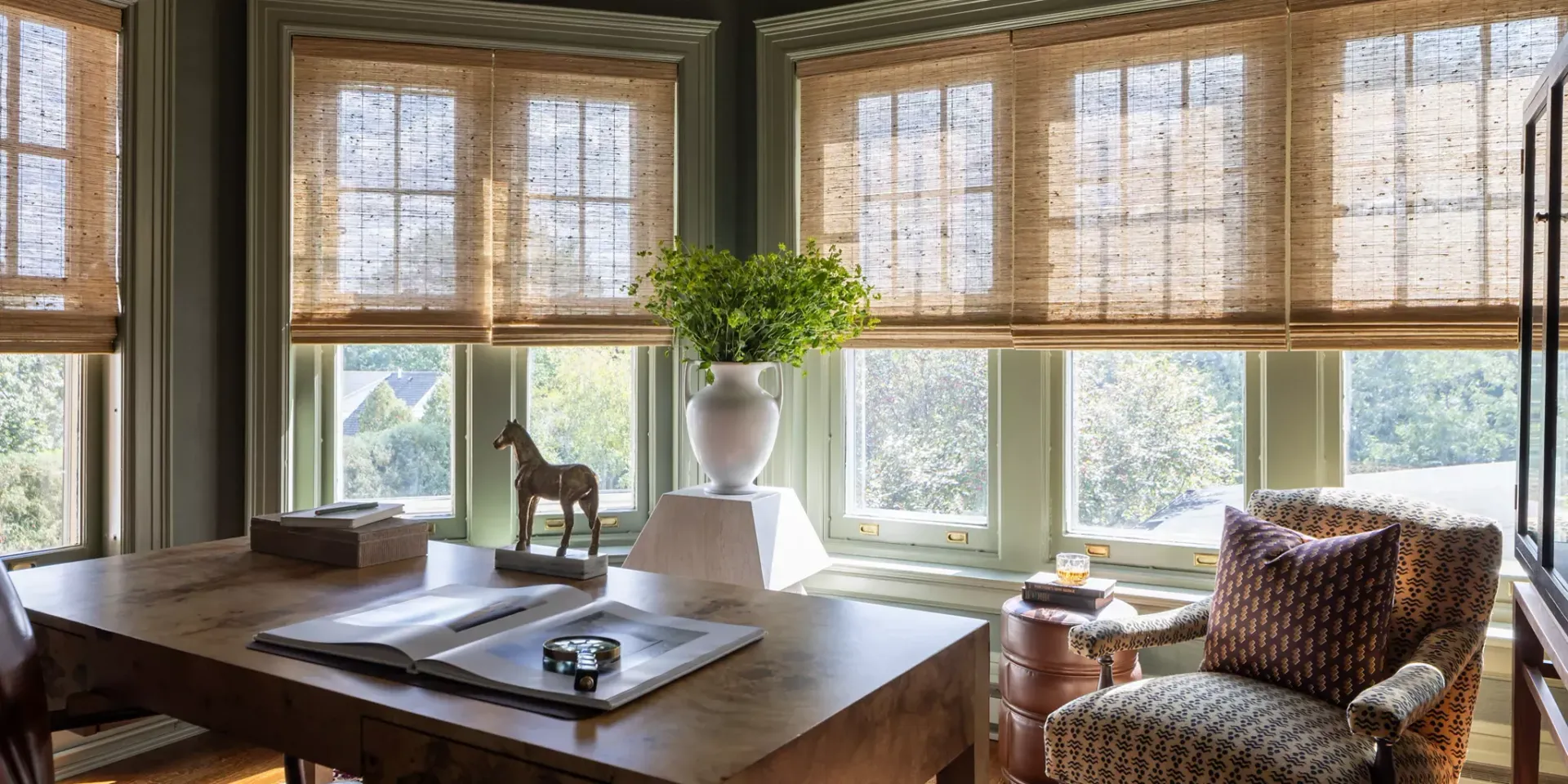 Sunlit cozy living room with woven shades, leather chair, wooden coffee table, and potted plant on the windowsill