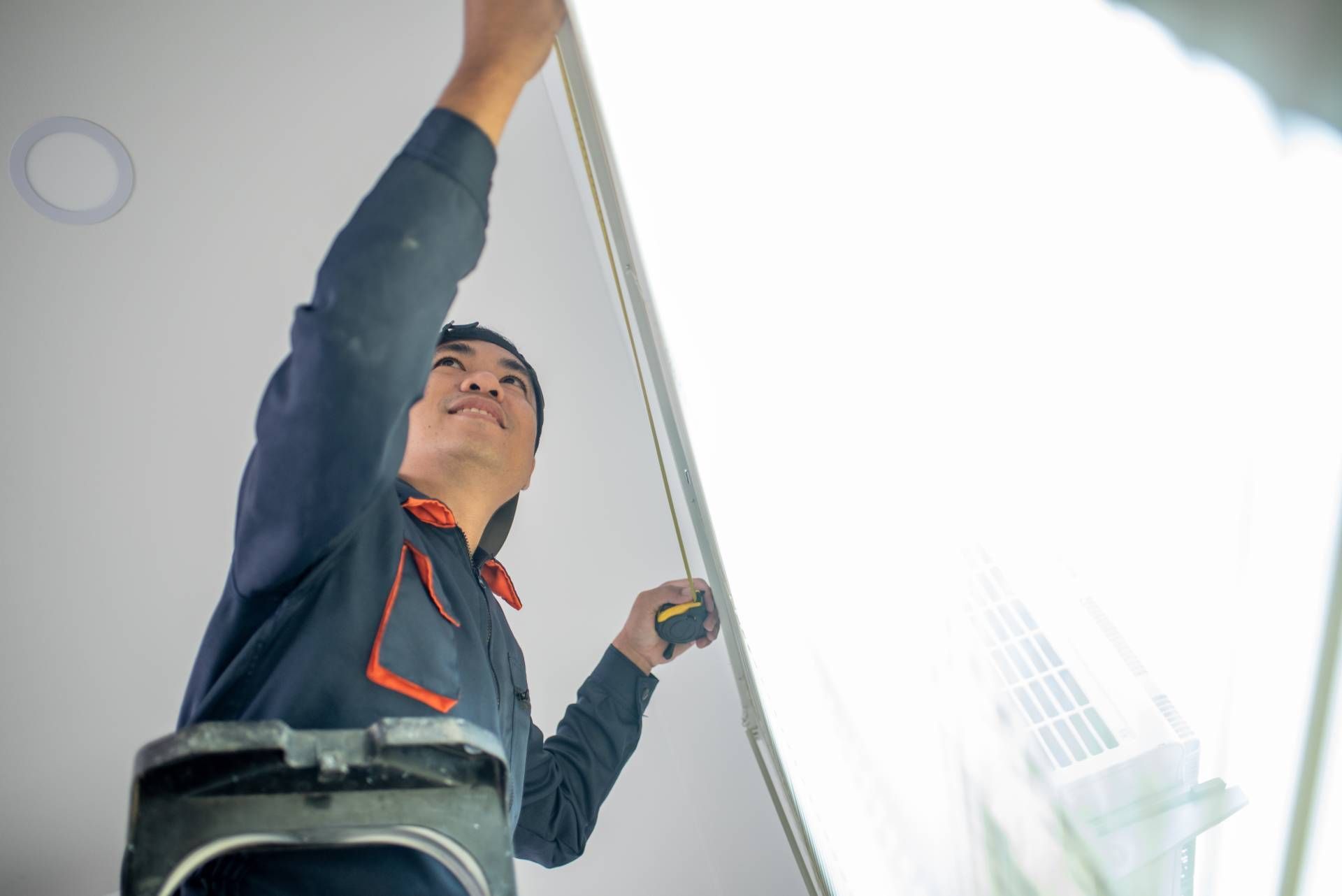 A professional installing a set of window blinds near Kalaheo, Hawaii.