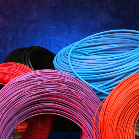 Un montón de carretes de cables de diferentes colores sobre un fondo azul.