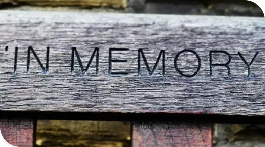 Wooden memorial plaque with the words “IN MEMORY” carved into weathered boards.