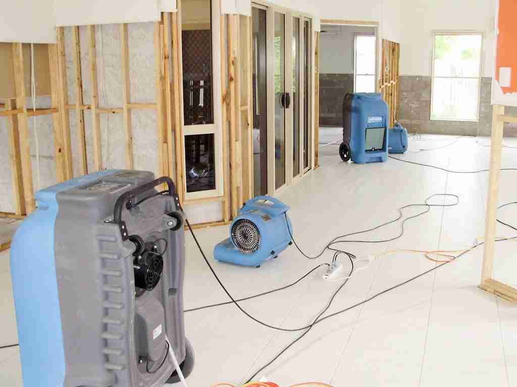 Two men are working on a washing machine and a refrigerator in a garage.