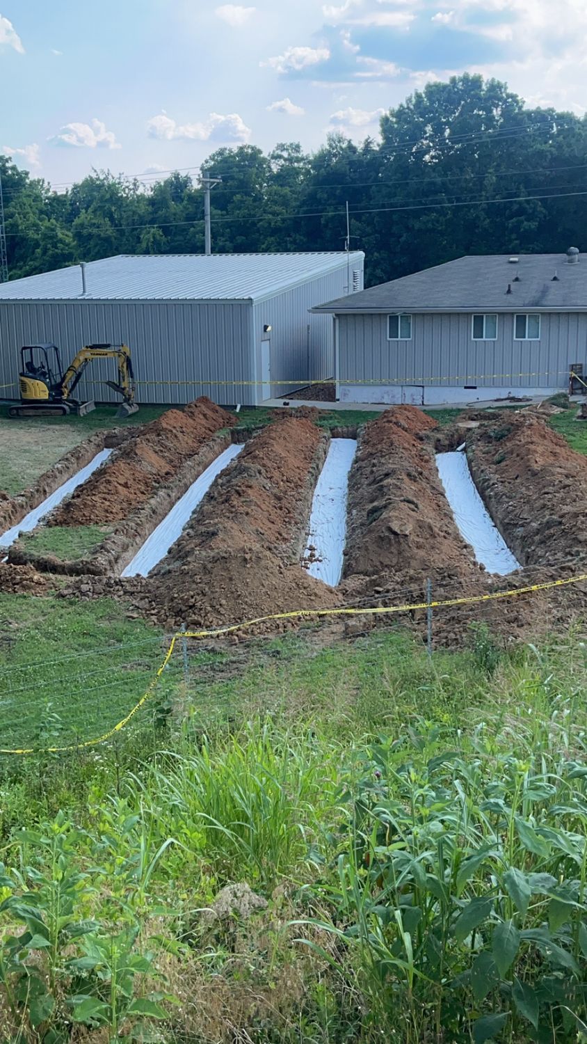 A large pile of dirt is being built in a field in front of a house.