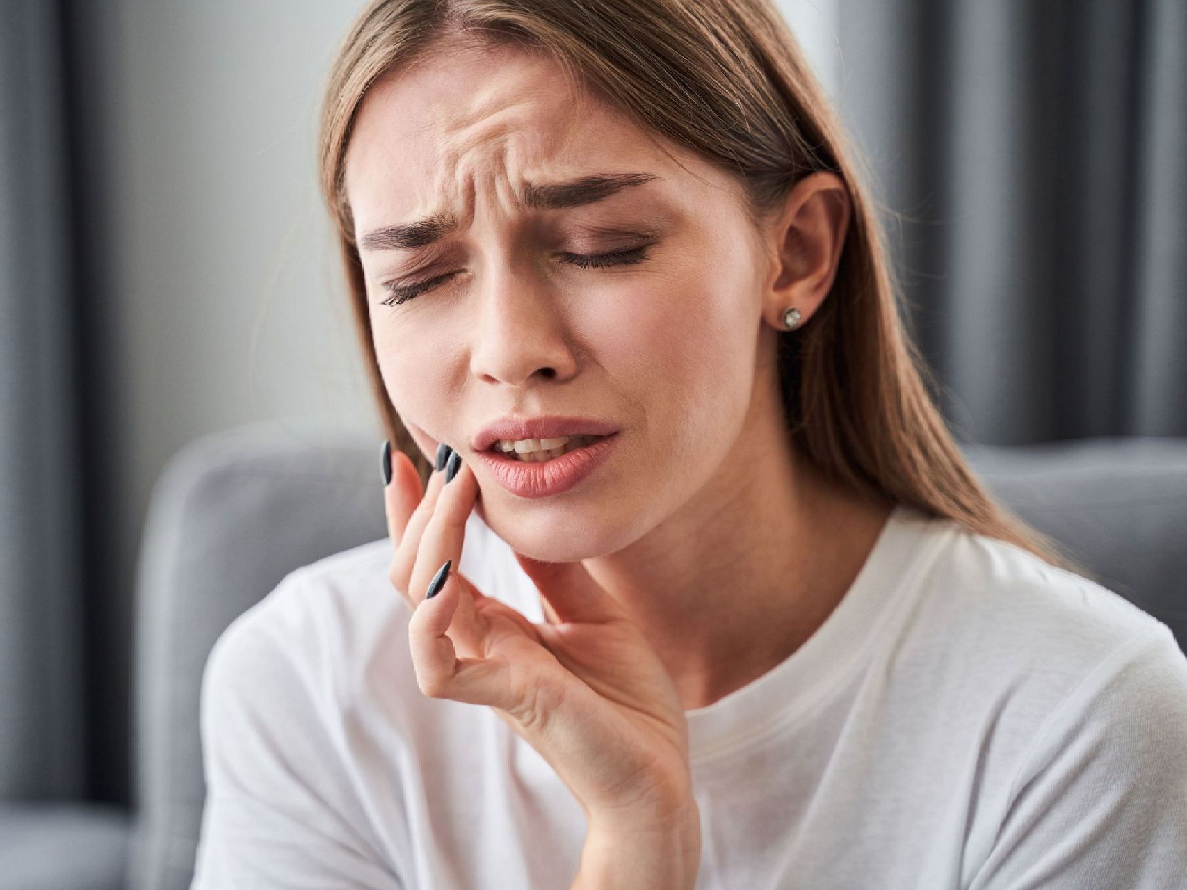 A woman is holding her face in pain because of a toothache