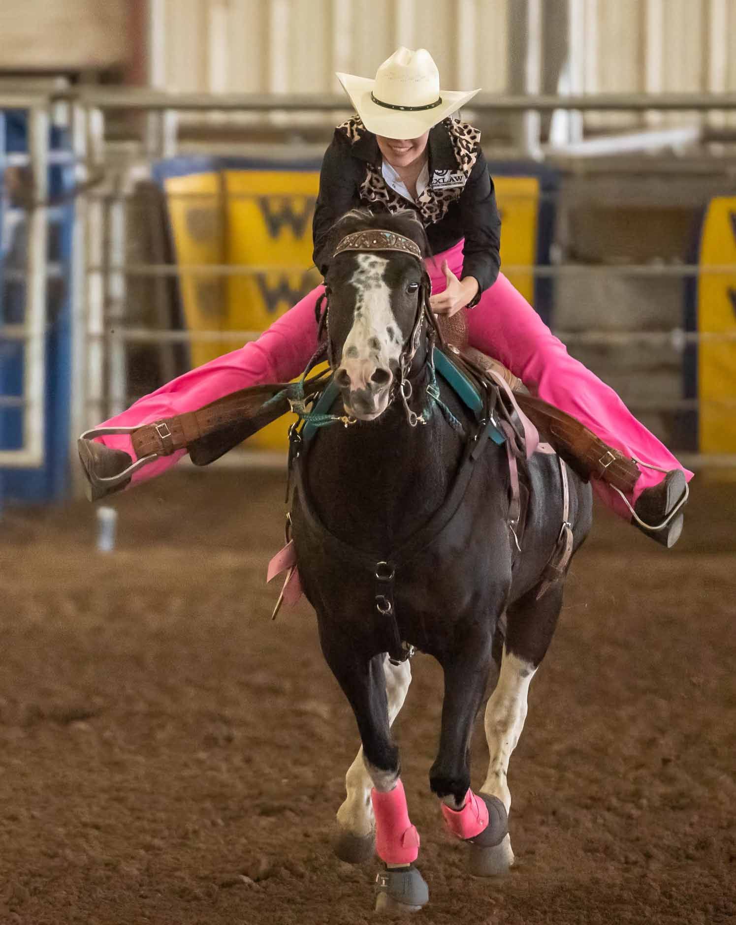 A woman in a cowboy hat is riding a black horse