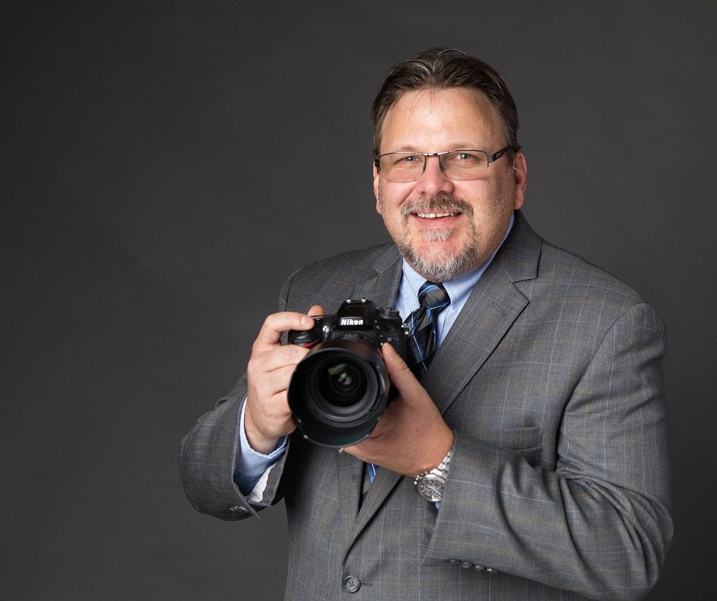 A man in a suit and tie is holding a camera.