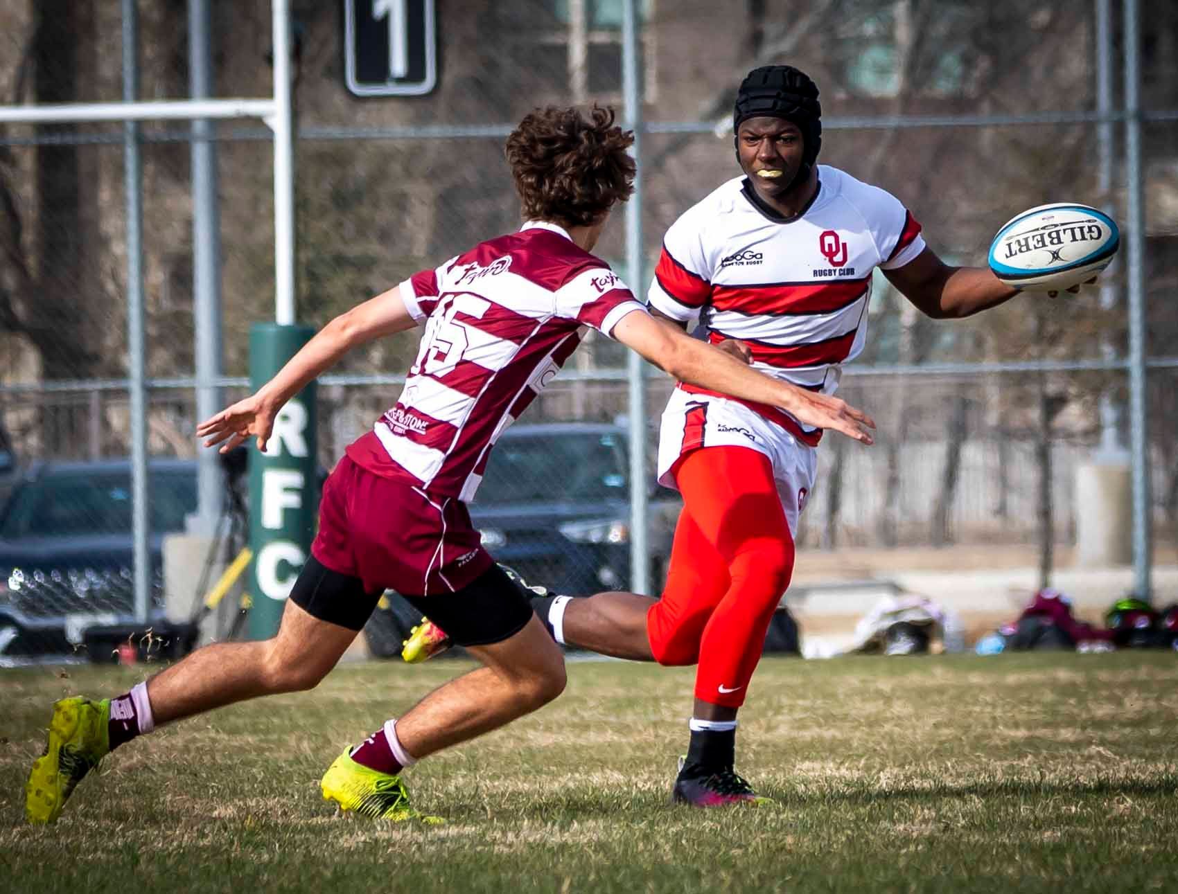 Two rugby players are playing a game of rugby on a field.