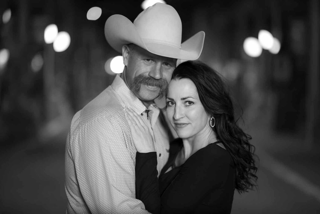 A man in a cowboy hat is hugging a woman in a black and white photo.