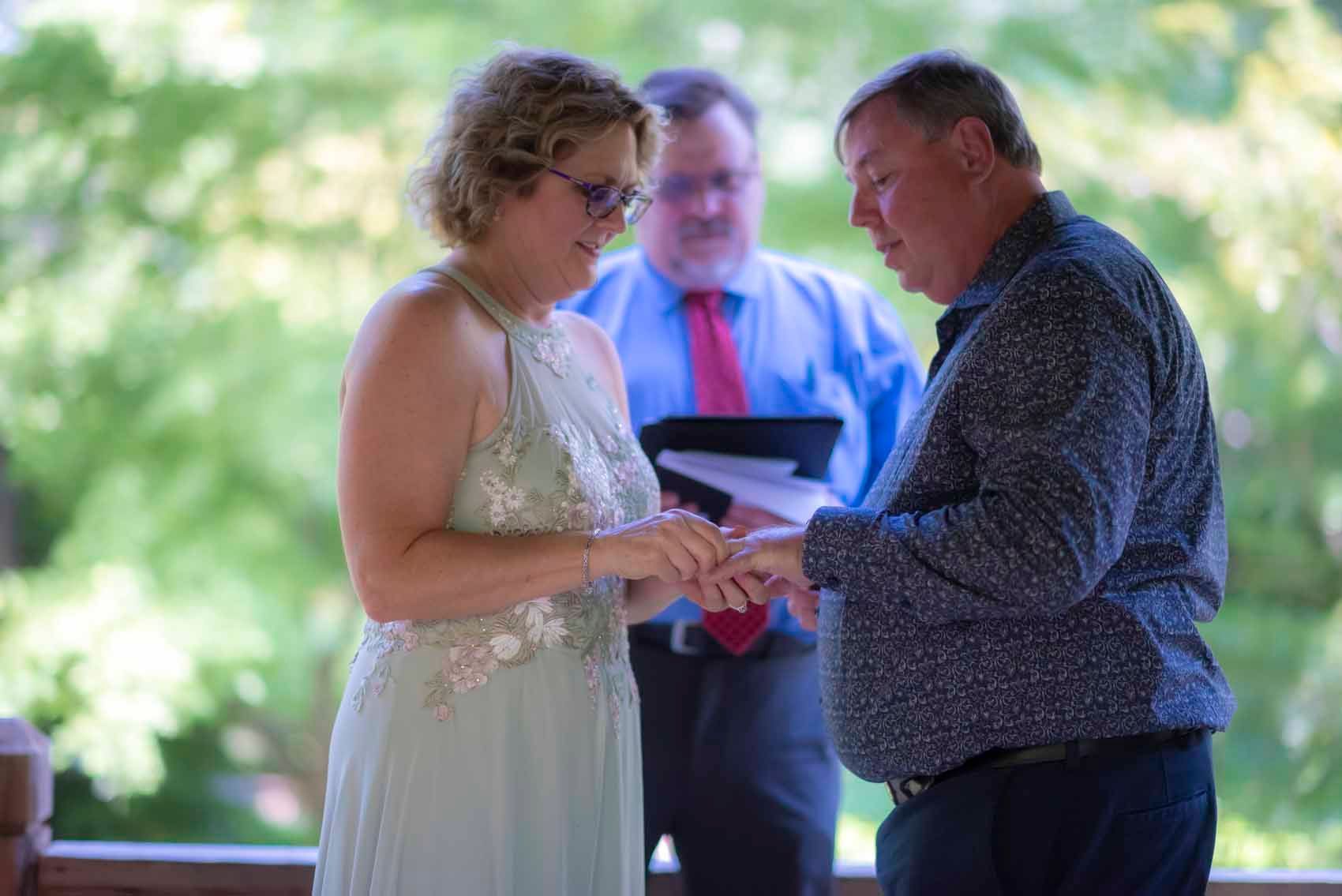 A man is putting a wedding ring on a woman 's finger.