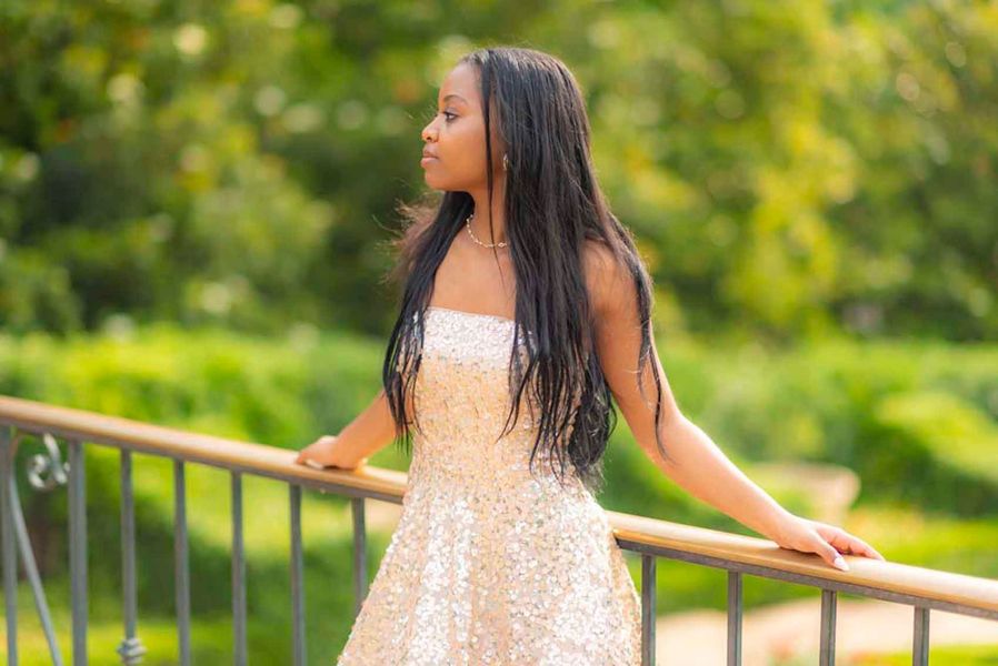 A woman in a white dress is leaning on a railing.