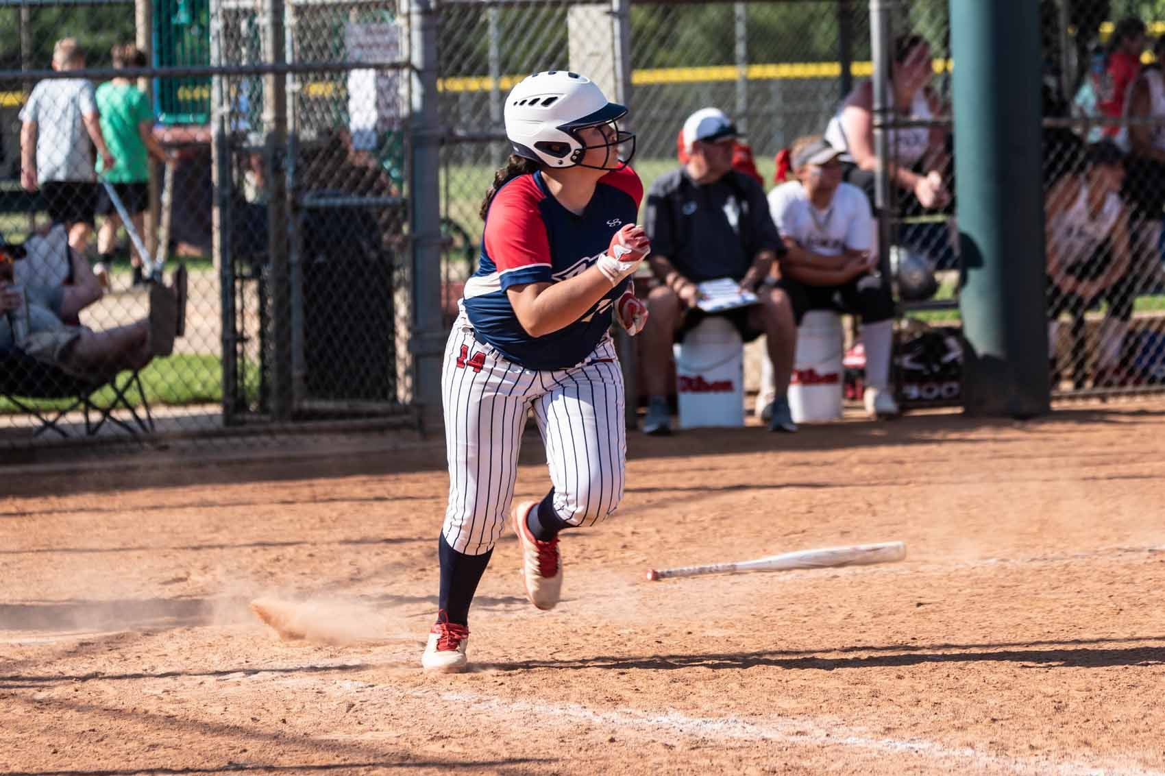 A woman is running to first base during a softball game.