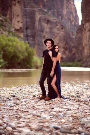 A man and a woman are standing next to each other on a rocky beach.