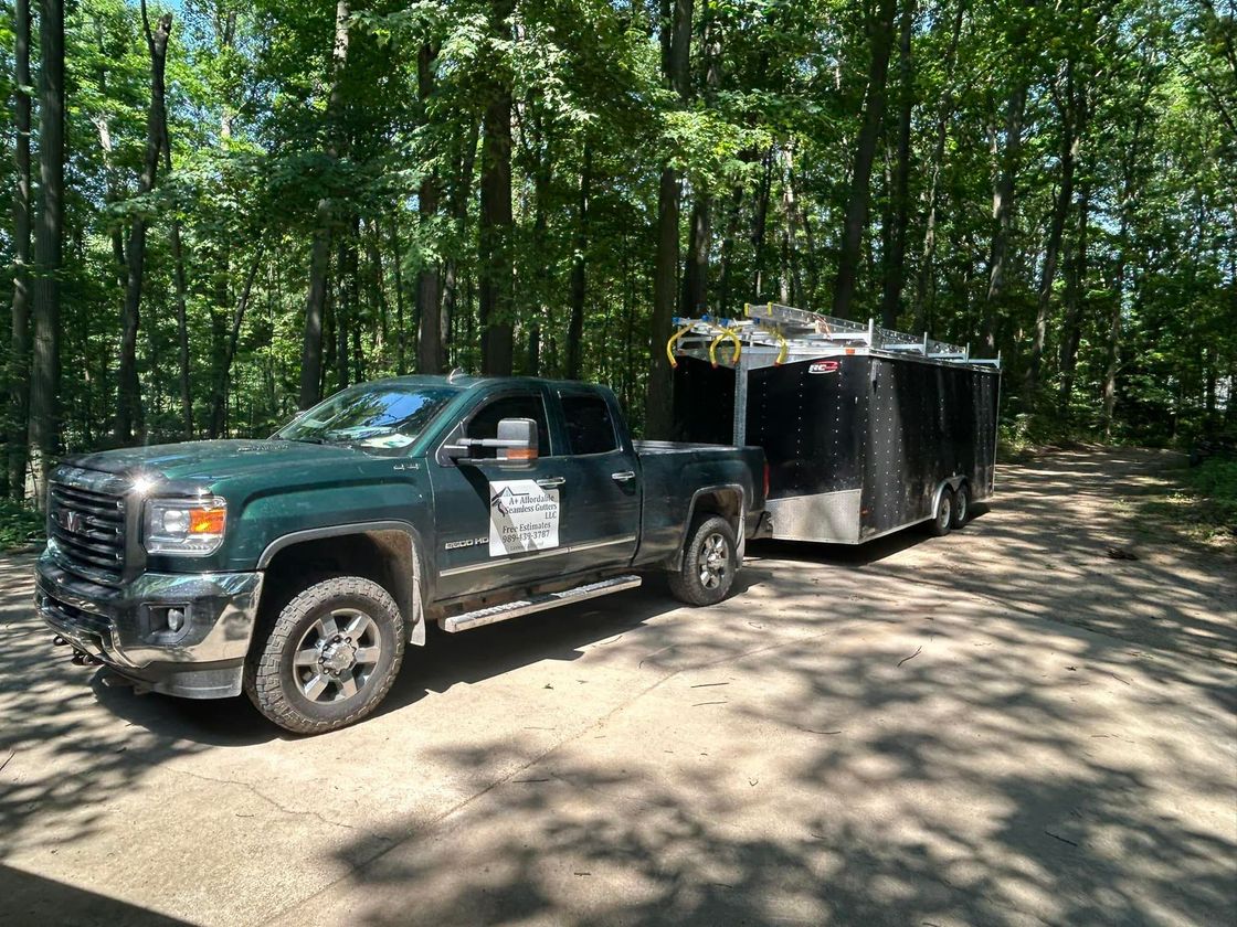 A truck is pulling a trailer down a dirt road.
