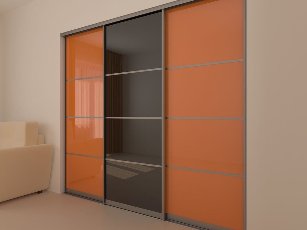 A Sliding Wardrobe With Orange and Black Doors in a Living Room — Wardrobe World In Paget, QLD