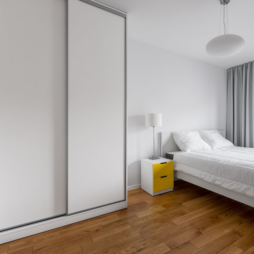 A Bedroom With a Bed, Nightstand, Lamp and Sliding Glass Doors — Wardrobe World In Paget, QLD