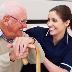 Nurse sits with her arm around an elderly patient. Horizontal shot