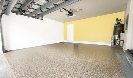 An empty garage with a yellow wall and a ceiling fan.