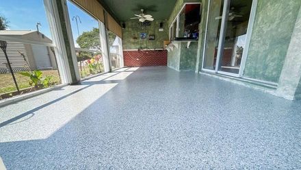 A porch with a concrete floor and a ceiling fan.