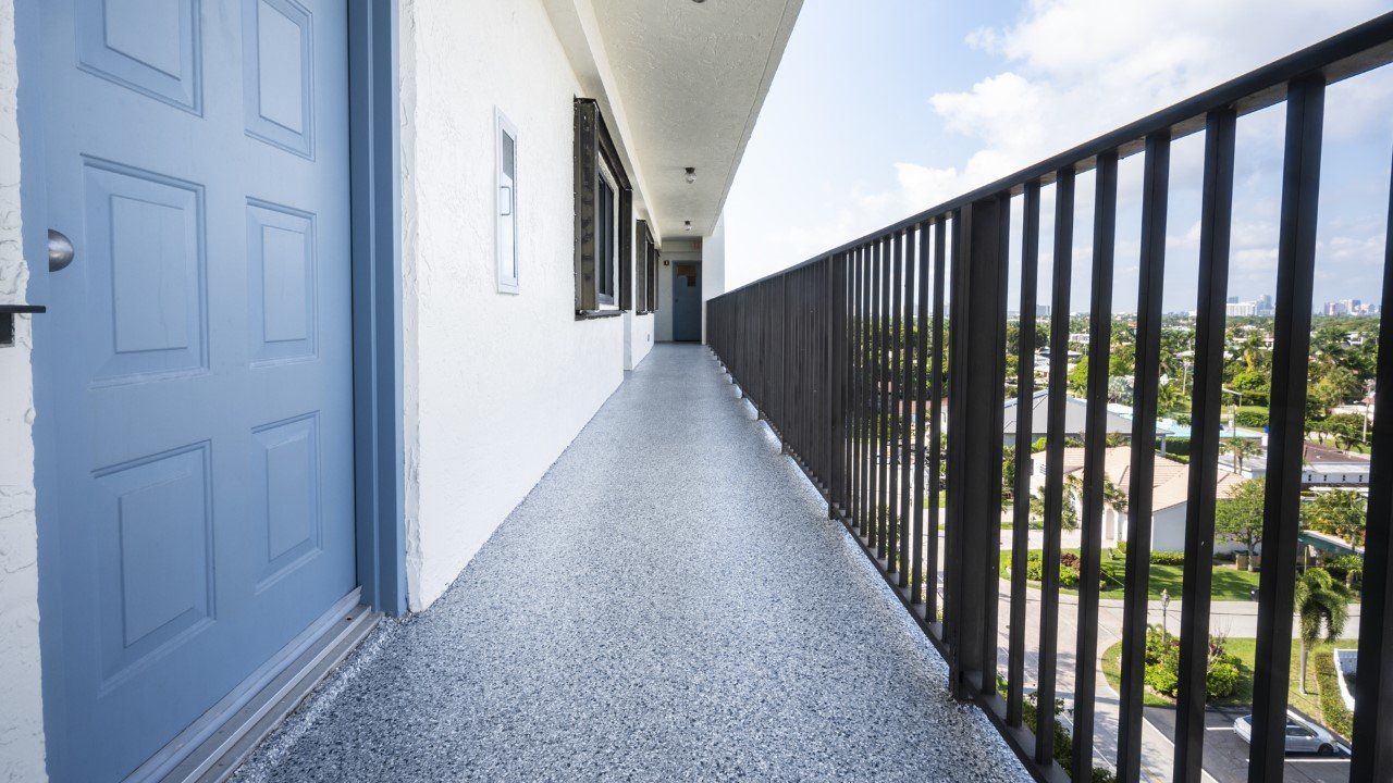 A long hallway with a balcony on the side of a building.