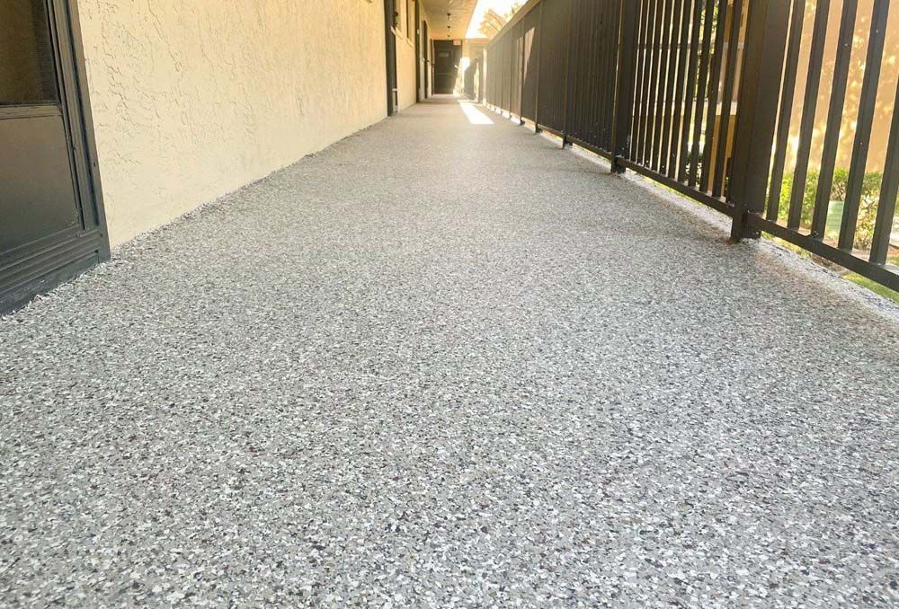 A long hallway with a railing and a gray floor.