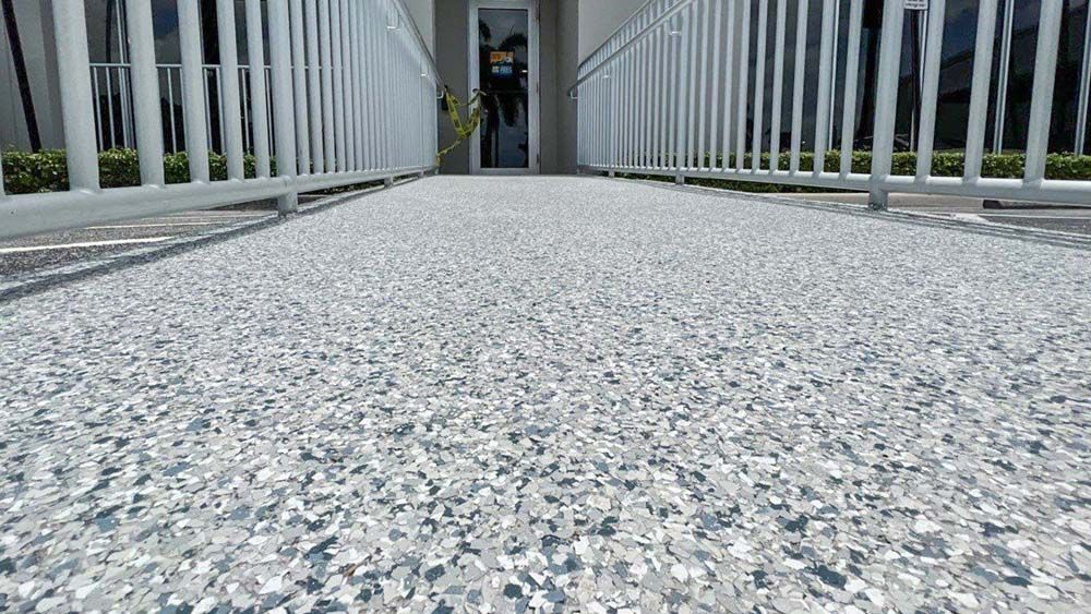 A concrete walkway leading to a building with a white railing.