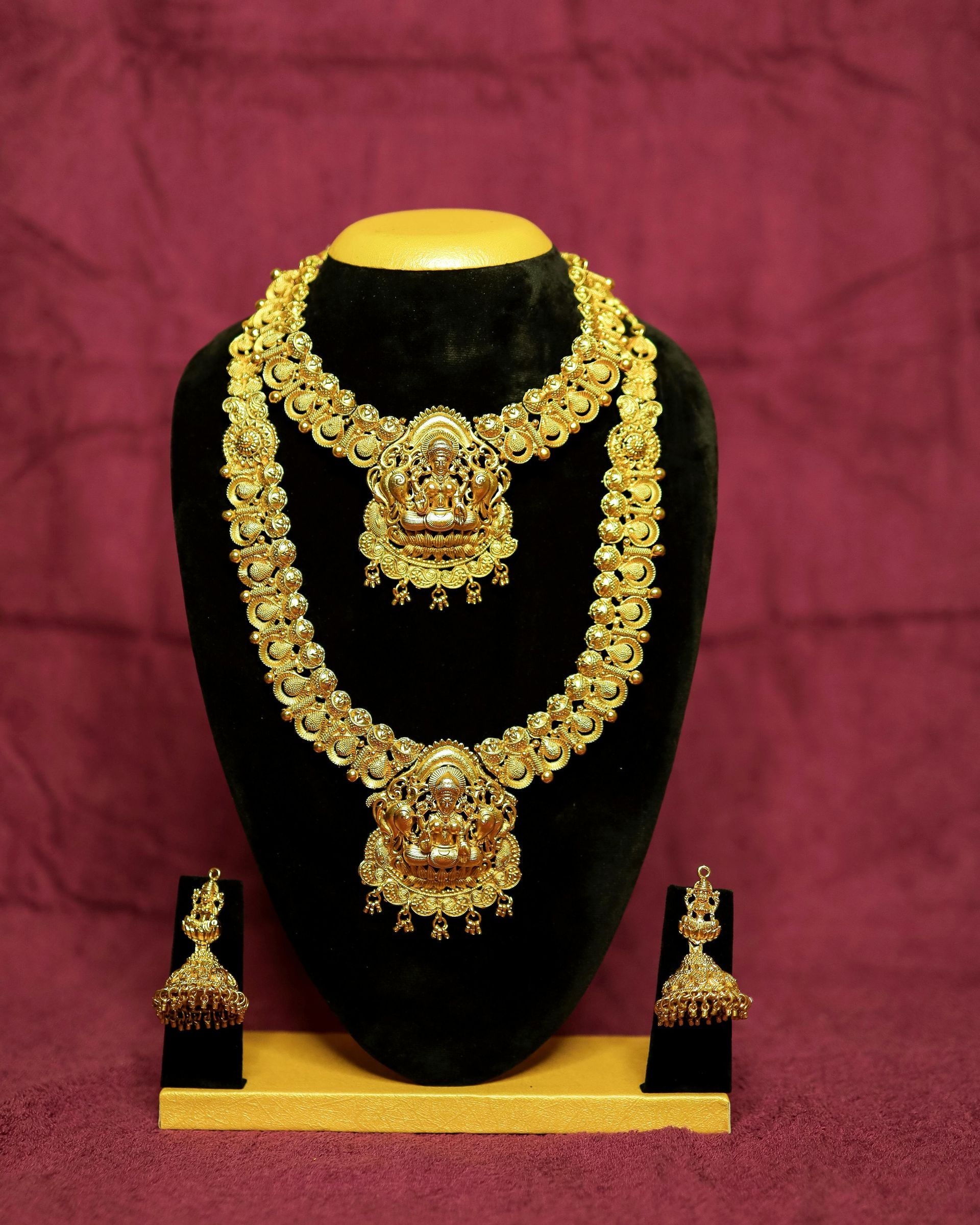 A gold necklace and earring set on a mannequin