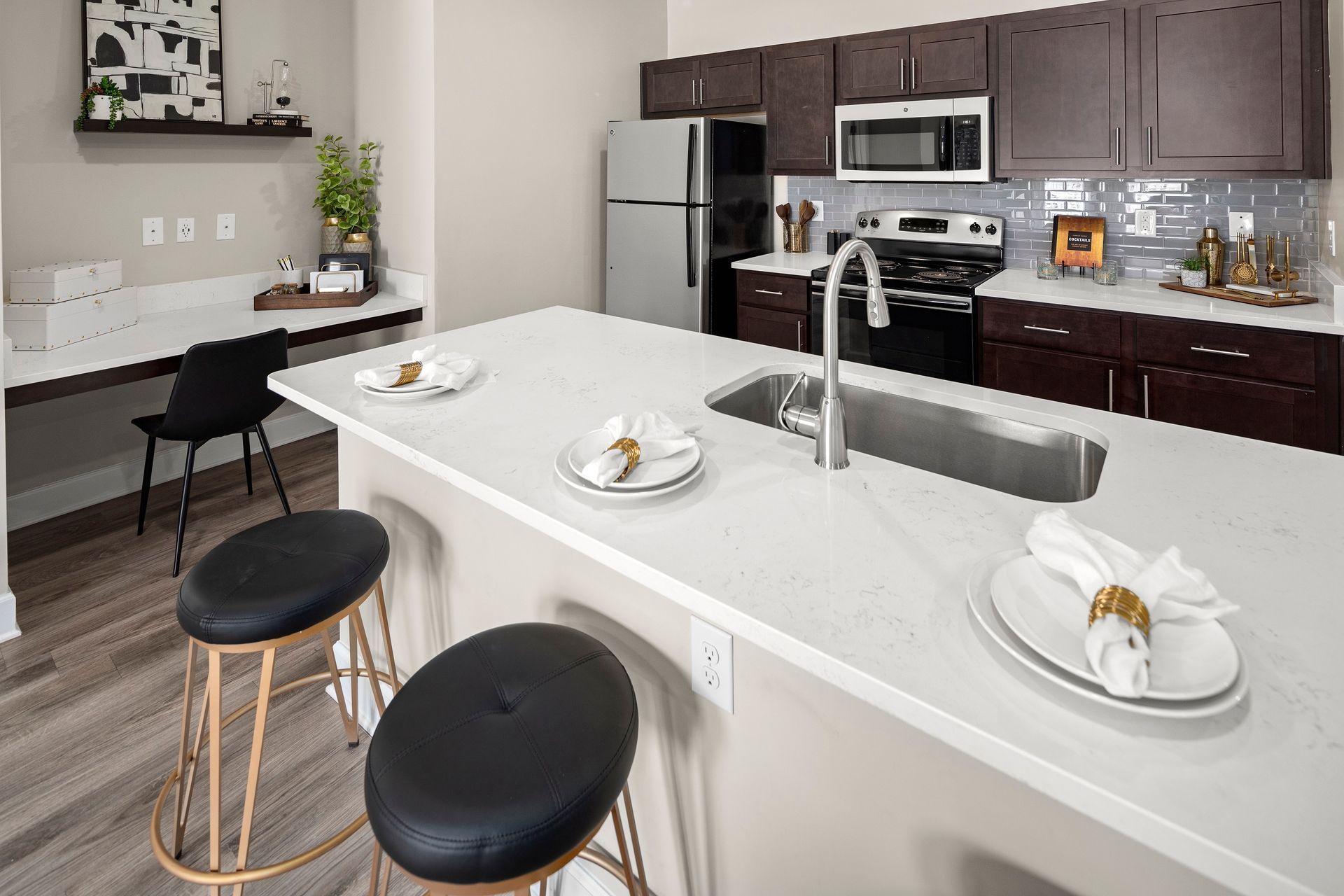 Modern kitchen with a breakfast bar, stools, and stainless steel appliances.