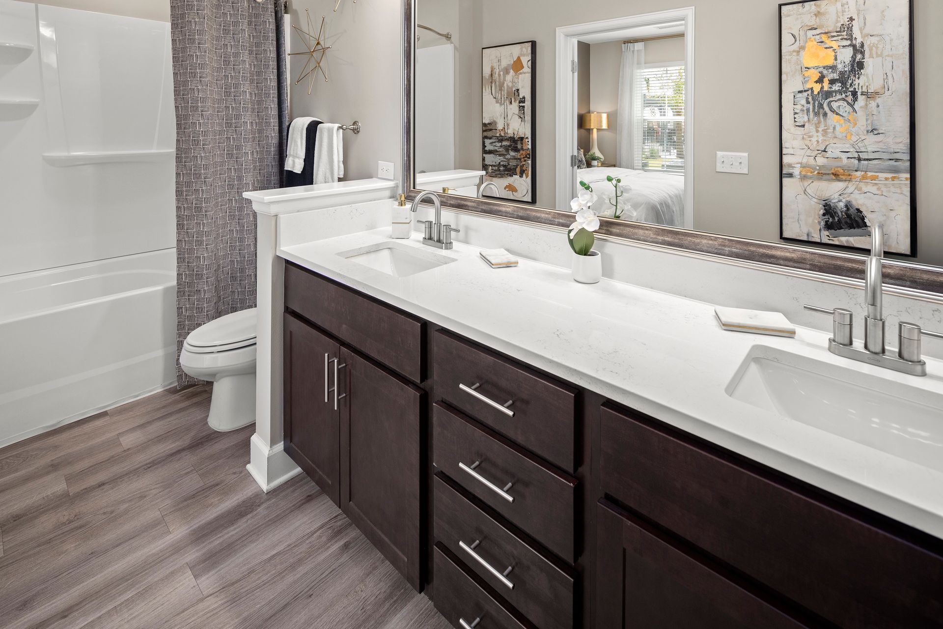 Bathroom with dark wood cabinets, double sinks, white countertop, and a shower/tub.