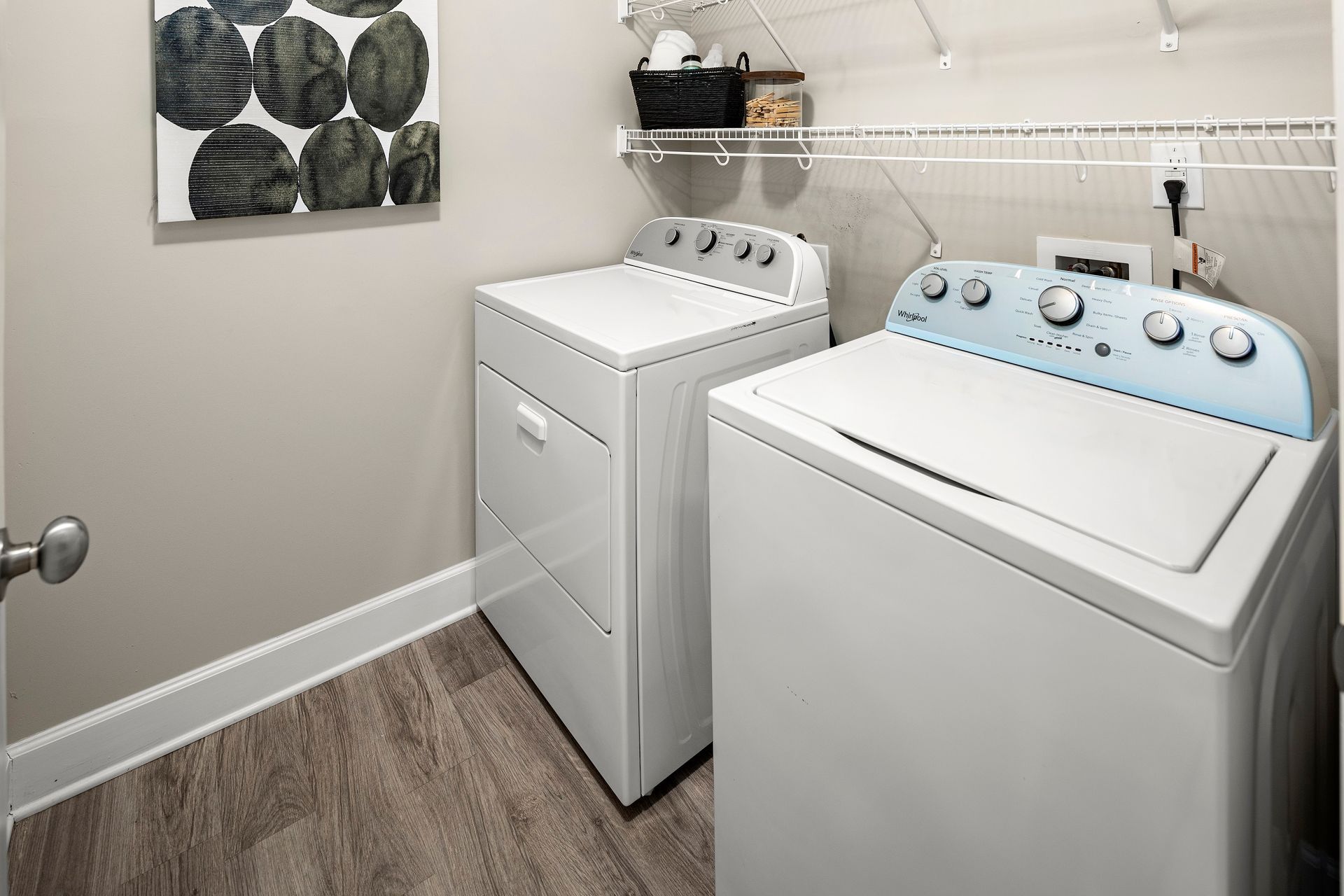 Laundry room with a washing machine, dryer, and a shelf with storage baskets and jars.