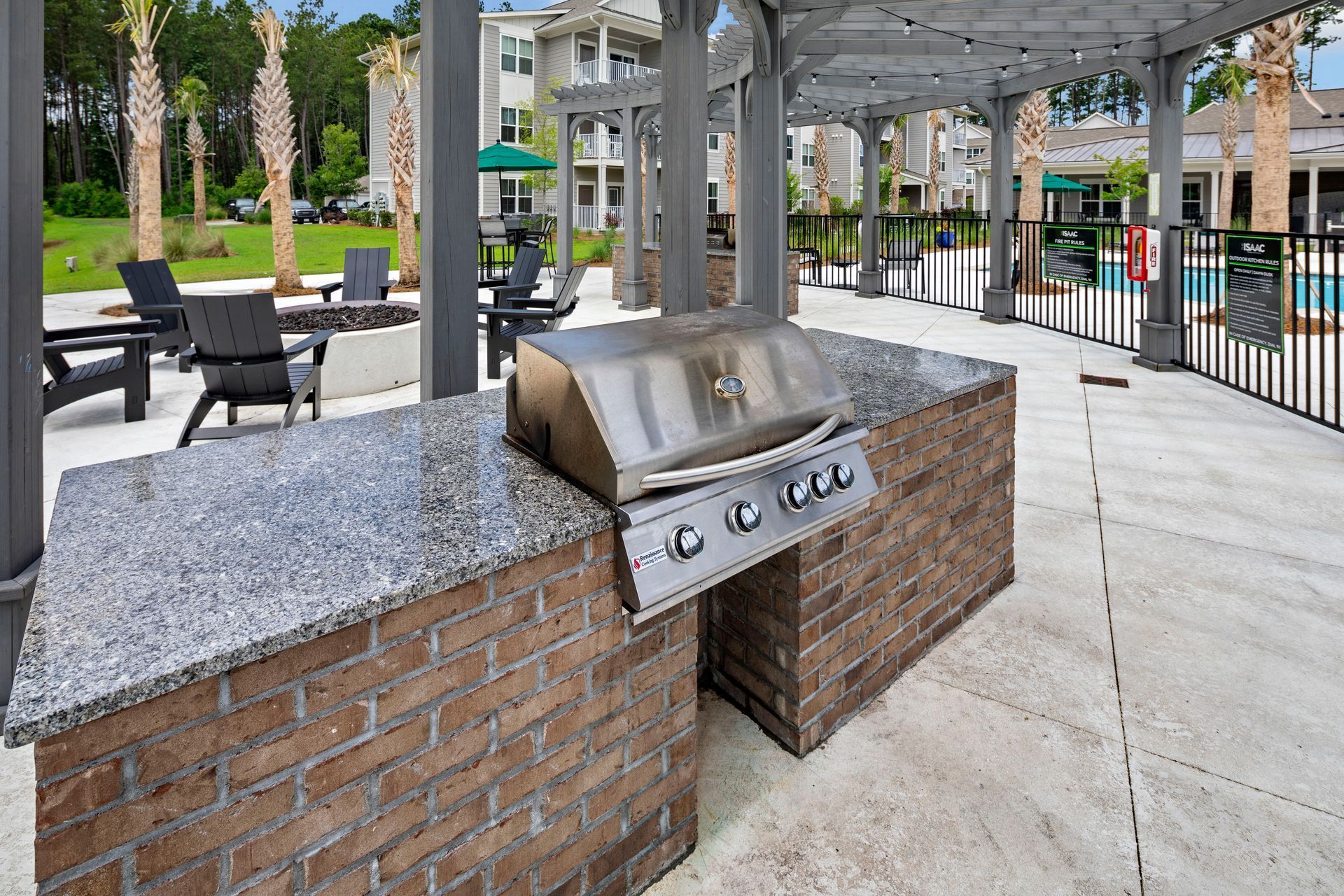 Outdoor grilling station with stainless steel grill, brick facade, and overhead pergola.